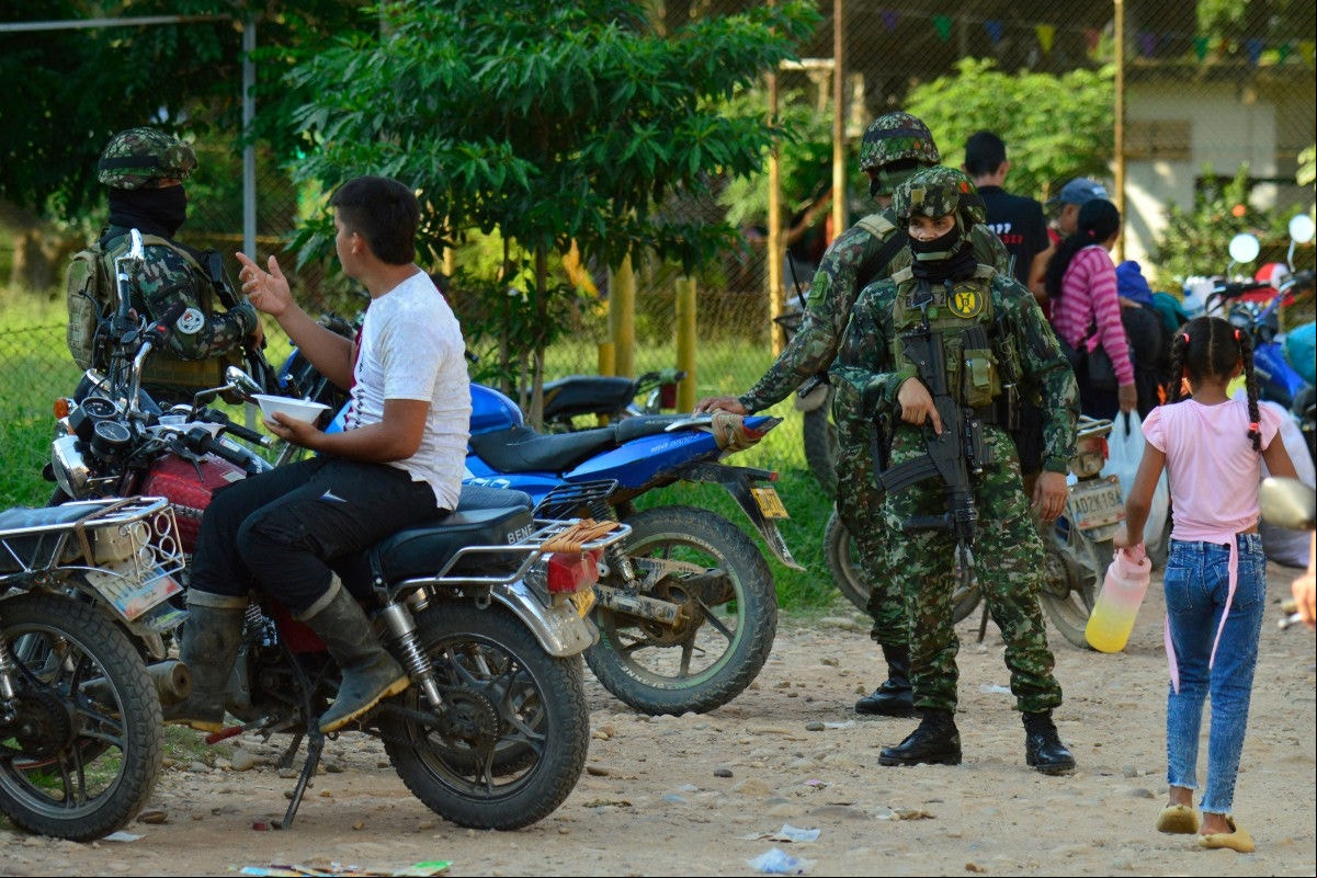 Soldados do exército colombiano montam guarda ao lado de pessoas deslocadas dos recentes confrontos entre grupos armados